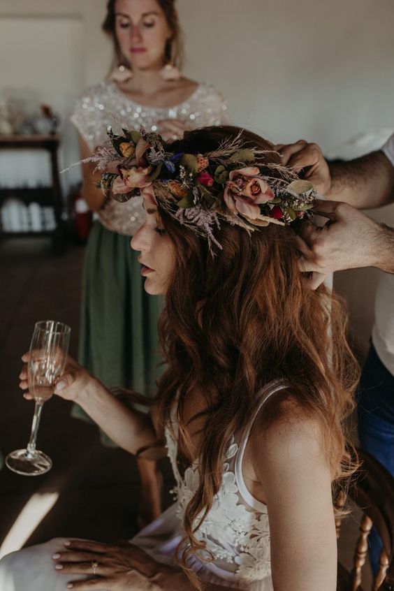 a fantastic moody flower crown with blue, red and pale rust blooms and dried leaves and herbs for a fall boho wedding