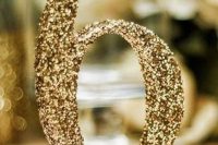 a gold glitter table number on a stand is a shiny and glam idea for reception tables and it can be easily DIYed