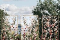 a gorgeous wedding backdrop of three sheer screens with lots of blush and burgundy blooms and greenery