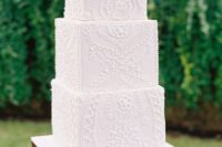 a gorgeous white square wedding cake all covered with lace looks like a real statement