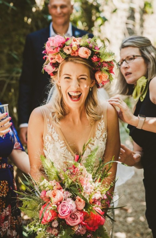 a jaw-dropping oversized colorful flower crown with pink, hot pink, peachy peonies and roses, billy balls, berries and fern is amazing for a colorful wedding