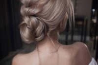 a low bun with a large dimensional braid on top forming a bun and ome locks down looks very chic