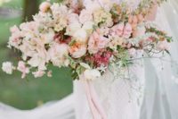 a lush and oversized blush wedding bouquet with neutral blooms and lots of greenery plus long ribbons