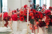 a lusha nd bold red winter wedding centerpiece with peonies, anemones, roses and tulips plus dark foliage is wow