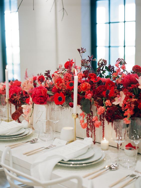 a lusha nd bold red winter wedding centerpiece with peonies, anemones, roses and tulips plus dark foliage is wow