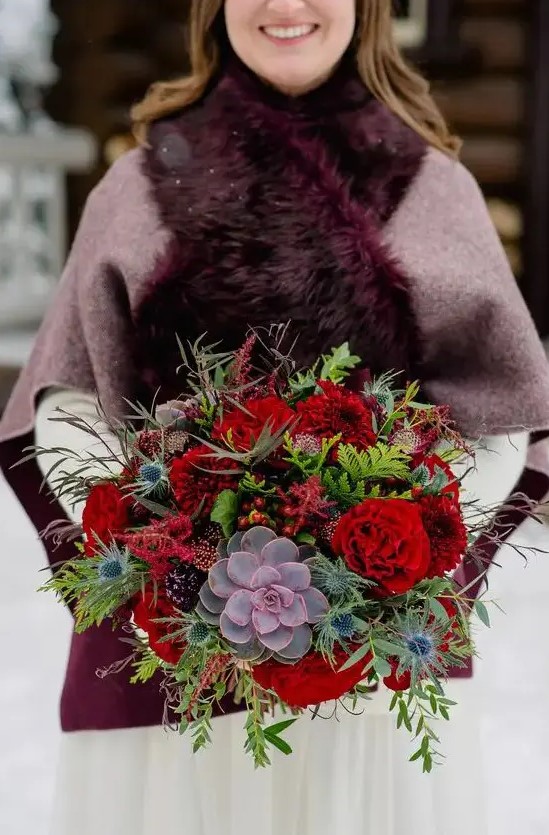 a luxurious and bright wedding bouquet with red blooms, berries, thistles, colorful succulents and greenery