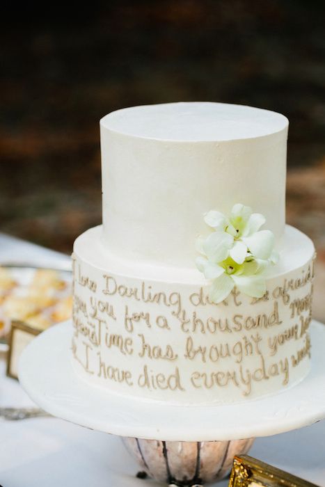 a neutral buttercream wedding cake with a gold love letter and white blooms is a chic and cool idea for a modern neutral wedding