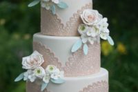 a neutral wedding cake with blush lace decor and sugar and fresh blooms for decor