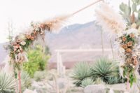 a non-traditional wedding arch of copper, with an irregular geometric shape and lush pastel blooms and foliage