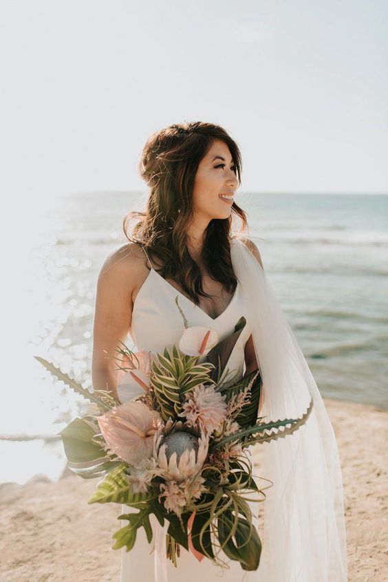 a pastel beach wedding bouquet with much greenery and lots of leaves plus air plants