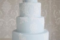 a powder blue wedding cake with white lace and monograms is a pastel piece with a tender touch