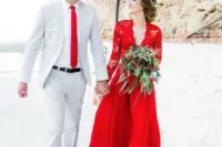 a red wedding dress with a lace bodice and long sleeves and a matching tie for the groom