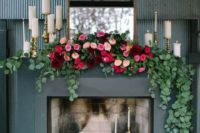 a refined modern fireplace as a wedding backdrop with pillar candles, bright lush florals and a large vintage mirror