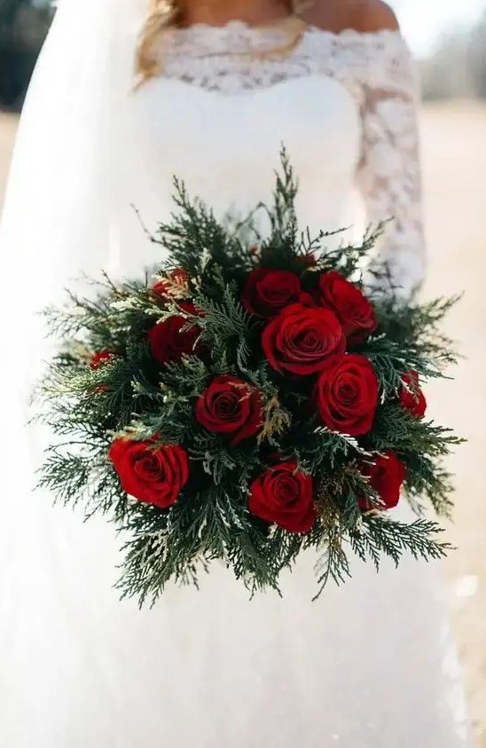 a simple holiday wedding bouquet of evergreens and red roses is a chic idea that always works
