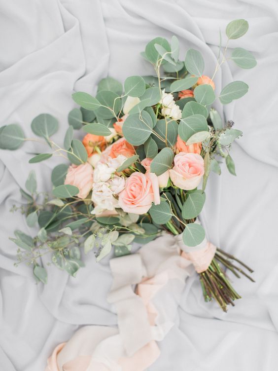 a simple wedding bouquet with blush and coral roses and eucalyptus with blush ribbons