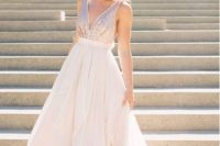a sleeveless light pink wedding gown with a sequin bodice and a plain full skirt, a plunging neckline