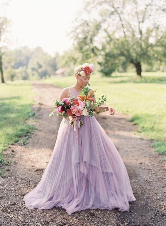 a sleeveless lilac wedding dress with a pleated layered maxi skirt with a train and an oversized floral crown