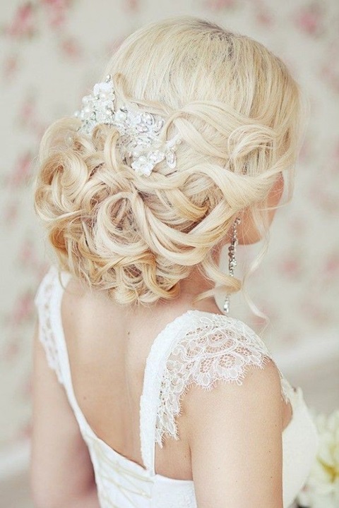 a stunning low wedding updo on long hair with a shiny rhinestone hairpiece and a slight volume on top