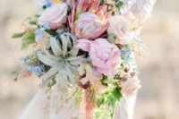 a unique cascading wedding bouquet in light pink and blue plus some neutrals, an air plant and much greenery