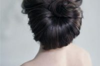 a unique retro-inspired low updo with a curled top and a twisted lower part for a retro bride