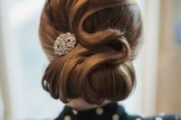 a vintage-inspired curled low updo with a shiny hairpiece and fixed waves is a great fit for a retro bride