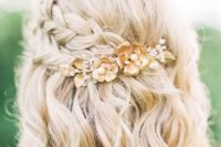 a wavy half updo with two side braids highlighted and secured with a floral hairpiece