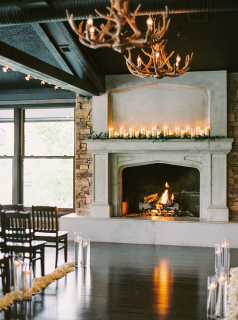 a wedding fireplace with pillar candles and greenery as a wedding backdrop is a cool idea to try