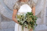 a white and gold glitter A-line wedding dress with short sleeves and a high neckline, a gold and green wedding bouquet for a lovely look