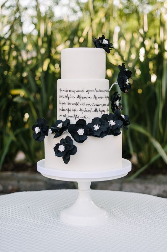 a white buttercream wedding cake with a love letter tier and black sugar blooms is an eye catchy solution for a black and white wedding