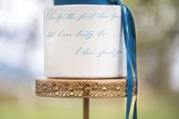 a white buttercream wedding cake with blue calligraphy  and a blue ribbon is a dreamy and chic idea for a wedding and a touch of something blue
