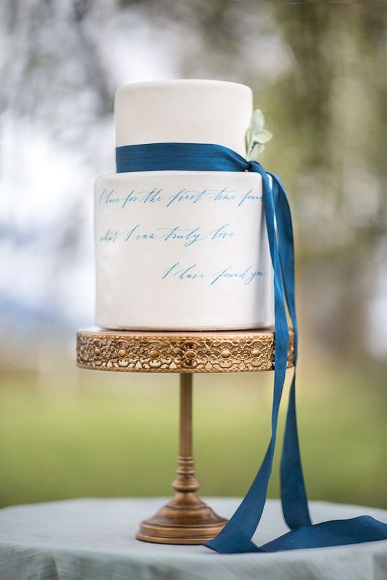 a white buttercream wedding cake with blue calligraphy  and a blue ribbon is a dreamy and chic idea for a wedding and a touch of something blue