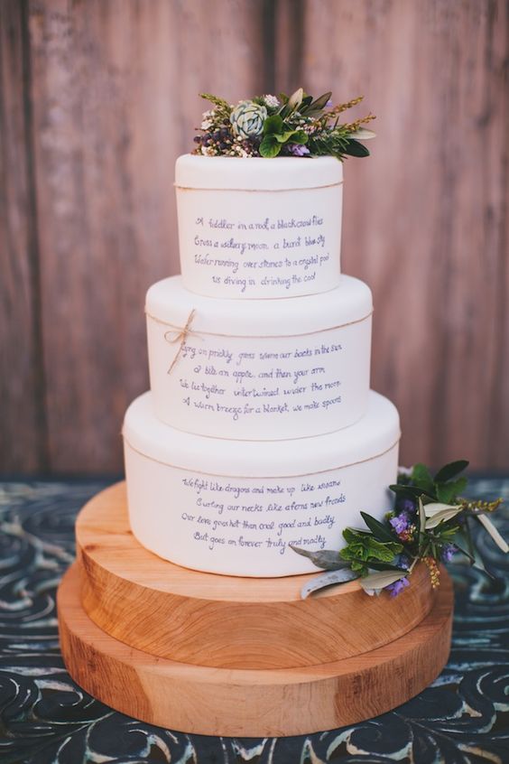 a white buttercream wedding cake with twine, love letters on each tier, greenery, succulents and some blooms