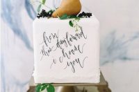 a white square wedding cake with a love letter, berries, greenery and a pear on top is a cool and chic idea for a summer or fall wedding