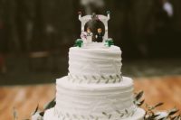 a white textural wedding cake with greenery and a creative wedding Lego cake toppers