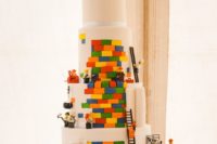 a white wedding cake with bright touches, lots of Lego figurines and cake toppers looks wow
