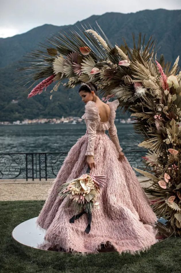 an amazing pink feather sparkling wedding ballgown with a cutout back and puff sleeves and a shiny headpiece for a royal-inspired wedding look
