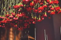 an overhead red flower wedding installation will substitute a wedding centerpiece and paired with black candles will create a wow effect