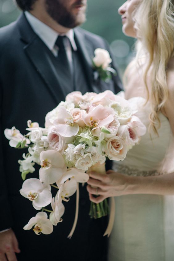 blush roses and peonies and white orchids for a beautiful cascading bouquet with a tropical feel