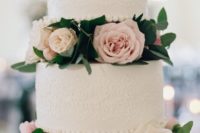 two white lace wedding cakes are highlighted with blush and neutral blooms in between