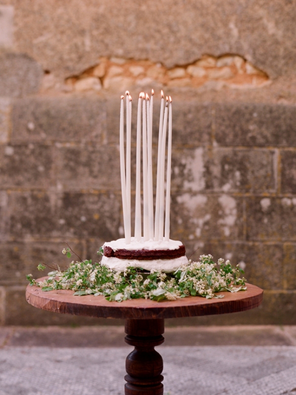 a naked wedding cake topped with thin and tall candles is a lovely wedding cake alternative that looks casual and cool