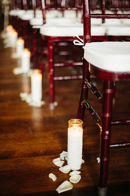 white candles in tall glasses and white petals are a nice decor idea for a wedding aisle, this is timeless classics that fits most of weddings