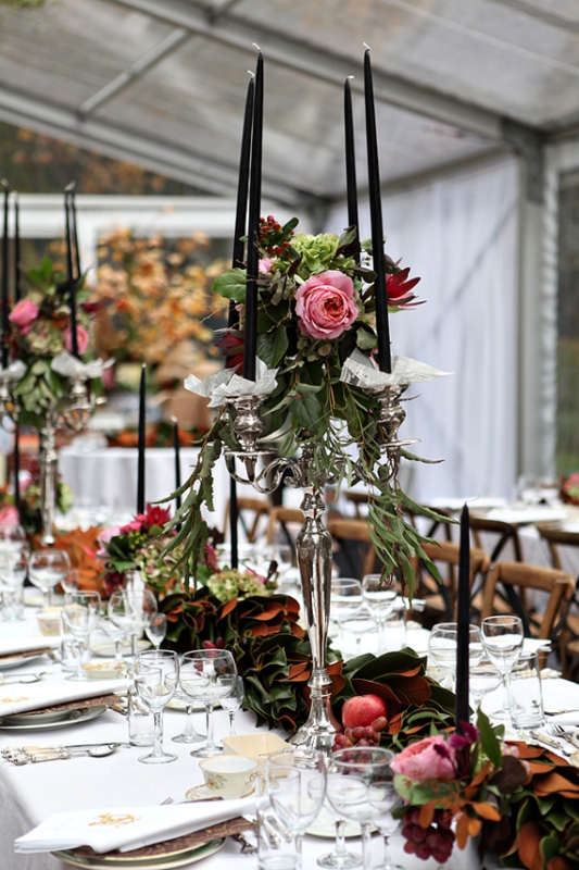 a bold floral and leaf garland on the table paired with tall candelabras decorated with blooms and black tall and thin candles
