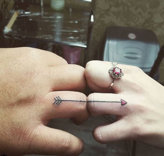 A romantic heart arrow wedding ring tattoos that is finishing on your partner's finger