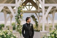 a black tuxedo with shiny lapels, a black shirt, black shoes and a shiny skinny tie that adds interest and a cool touch to the look