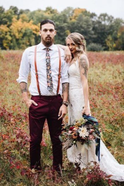 a boho groom's look with a white shirt, a floral tie, burgundy pants, amber leather suspenders for summer