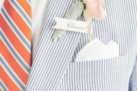 a bold groom’s outfit with a blue striped blazer, a white shirt, an orange and blue striped tie, a blush flower boutonniere