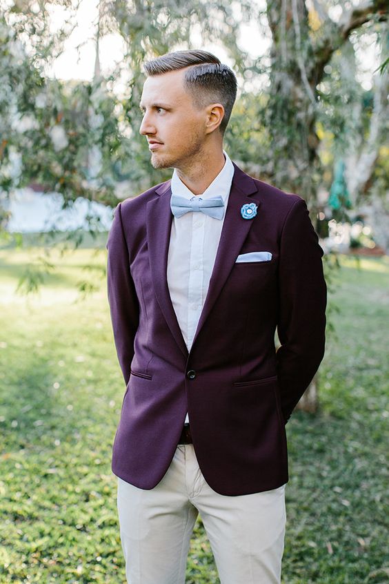 a bold groom's outfit with a purple blazer, a white shirt, a light blue bow tie and handkerchief, neutral pants