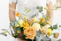 a bold wedding bouquet of yellow and peachy blooms, greenery and grasses looks textural, catchy and dimensional