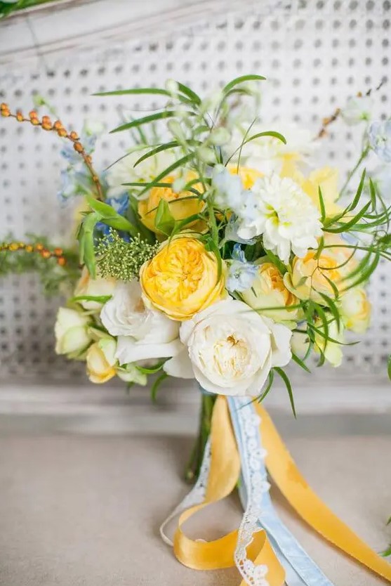 a bright and cool wedding bouquet with yellow and neutral blooms, touches of blue, greenery and long ribbons