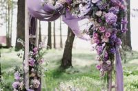 a bright lilac, purple and pink wedding arch with airy fabric for a romantic touch